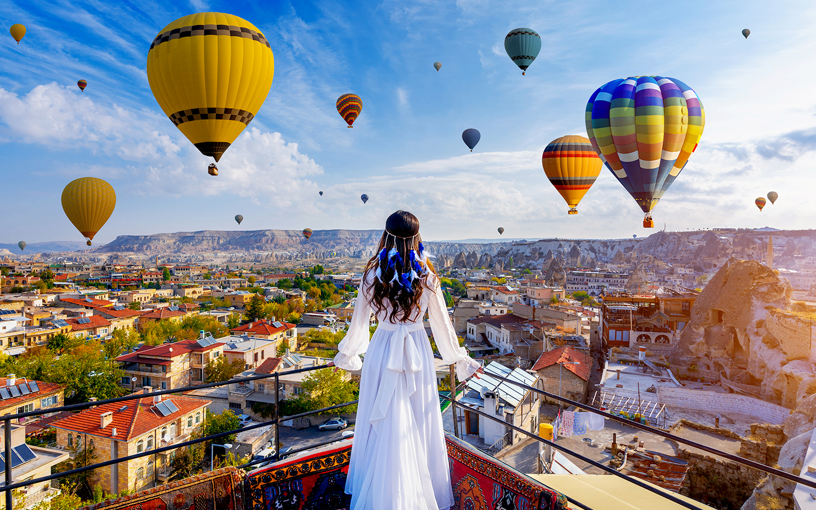Multiple balloons floating above Cappadocia valleys at sunrise